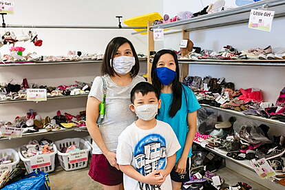 A mom and her two kids stand in the shoe section for a happy family photo.